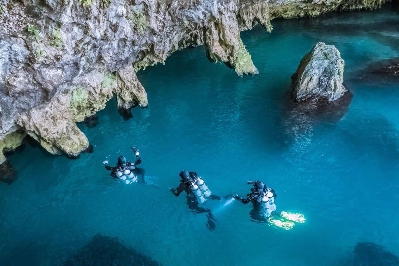 洞穴潜水探测队员在地下暗河蓝色水域进行探测